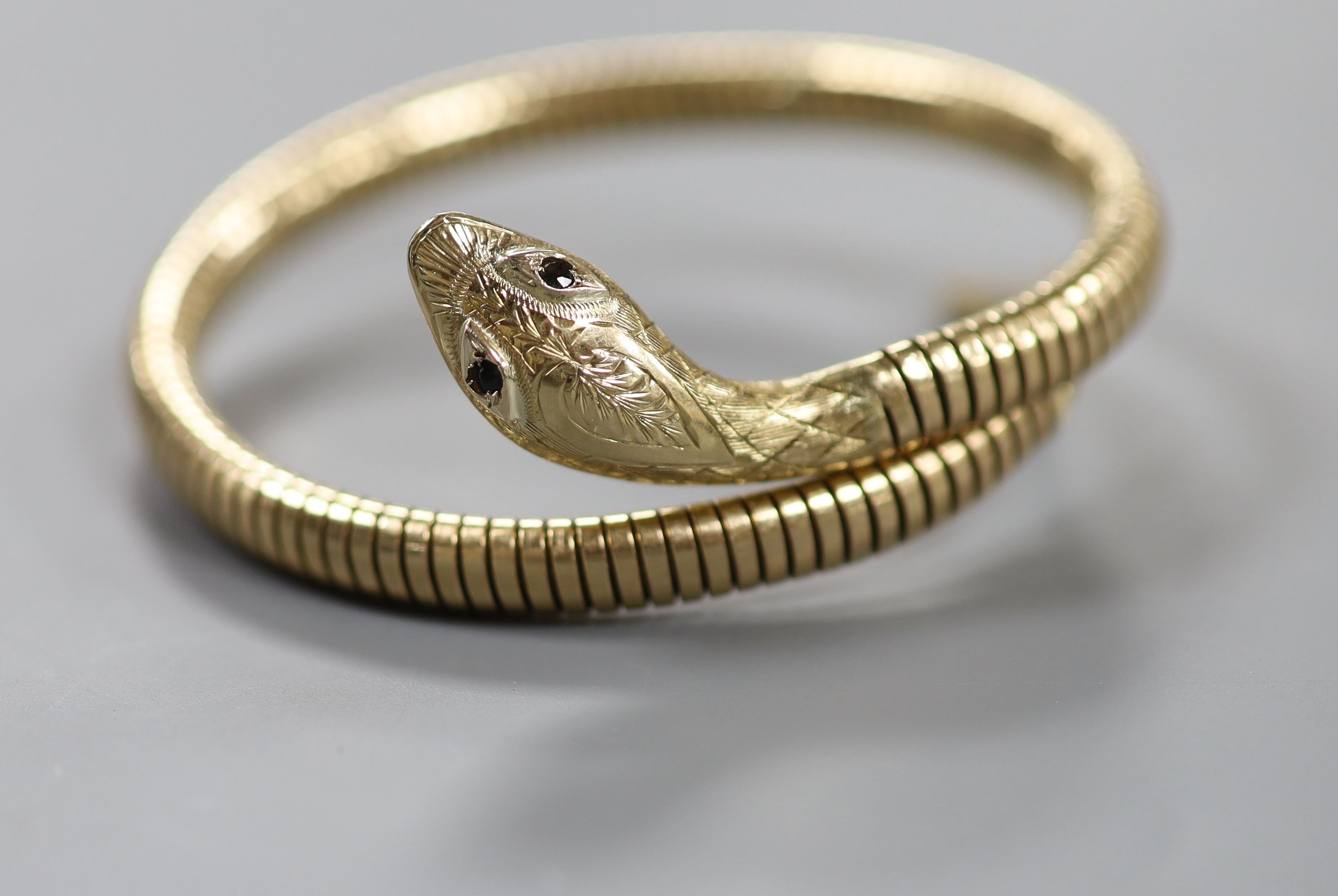 A mid 20th century 9ct gold coiled serpent bracelet, with gem set eyes, gross weight 22.4 grams (metal spring) (a.f.).